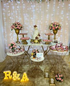 a table topped with lots of cake next to two vases filled with pink flowers