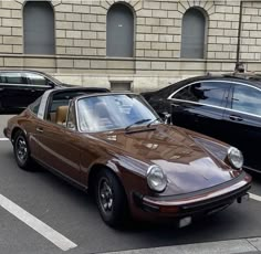 a brown car parked next to another black car in a parking lot with other cars