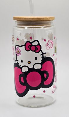 a hello kitty glass jar with a straw in the top and lid is decorated with pink flowers and stars