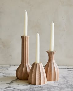 three wooden candlesticks sitting on top of a marble table