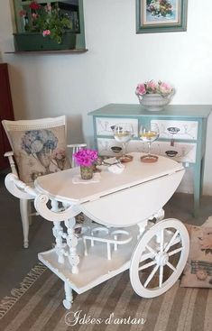 a table and chairs in a room with flowers on the table, next to an old fashioned wagon