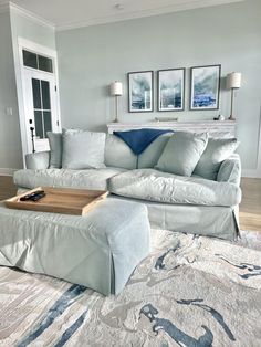 a living room with white furniture and blue accents