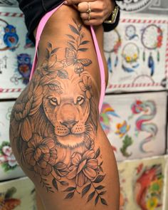 a woman's thigh with a lion and flowers tattoo on the side of her leg