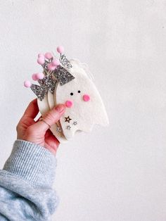 a person holding up a small white brooch with pink and silver decorations on it