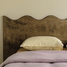 a bed with two pillows on top of it and a wooden headboard behind it