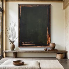 a painting is hanging on the wall above a table with two vases and a bowl