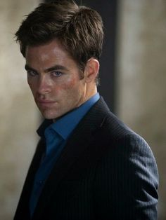 a man in a suit and blue shirt looking at the camera with serious look on his face