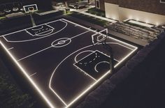 an aerial view of a basketball court lit up at night with lights on the floor