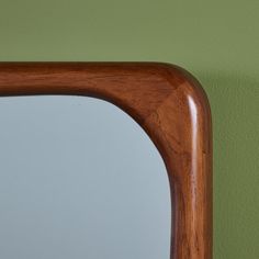 a wooden frame mirror against a green wall