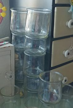 there are many empty glasses on the table next to an old dresser and other items