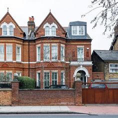 a large brick building with many windows and doors on the front of it, next to a fence