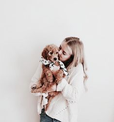 a woman holding a dog in her arms and kissing it's face with both hands