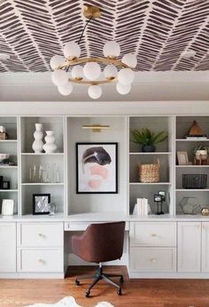 an office with white bookcases and a brown chair in front of the desk