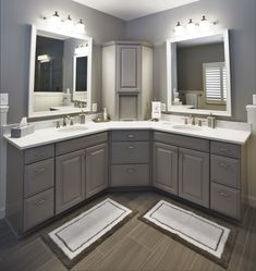 a large bathroom with two sinks, mirrors and rugs on the floor in front of them