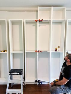 a man is sitting on a step stool in front of shelves with tools and construction equipment