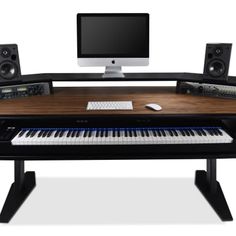 a computer desk with a keyboard, monitor and speakers on top of it in front of a white background