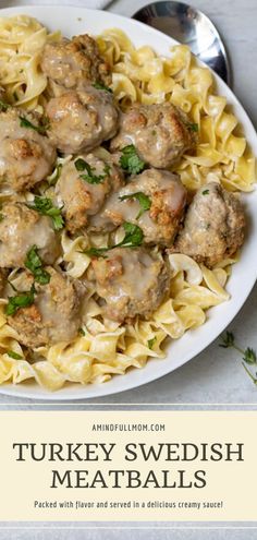 a white plate topped with meatballs covered in gravy next to a fork