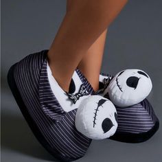 a woman's feet wearing striped slippers with panda face on the soles