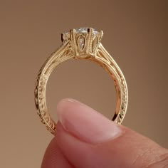 a close up of a person holding a gold ring with a diamond in it's center