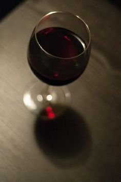 a glass of wine sitting on top of a wooden table