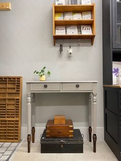 a room with some shelves and drawers on the wall next to a table that has a wooden box on it