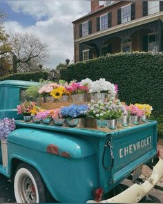 an old blue truck with flowers on the back