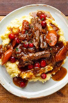 a white plate topped with mashed potatoes covered in meat and vegtables