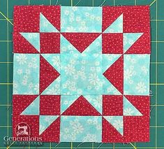 a red and blue quilted block on a green cutting mat with scissors next to it