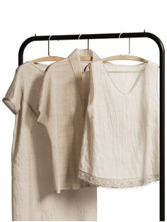 two white shirts hanging on clothes racks next to each other