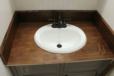 a white sink sitting on top of a wooden counter