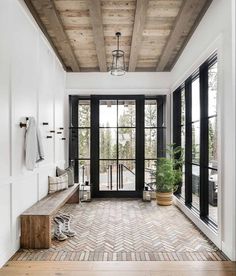 the entryway is decorated in white and black with herringbone tile flooring that matches the wood ceiling