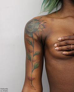 a woman with green hair has tattoos on her chest and is showing off her breast