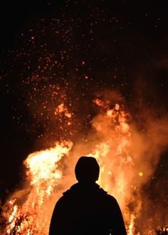 a man standing in front of a large fire