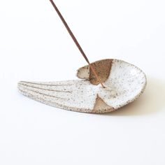 a white bird shaped dish with two brown sticks sticking out of it's side