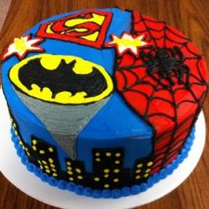 a birthday cake decorated to look like a batman and spiderman theme on a wooden table