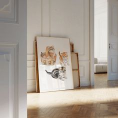 there is a cat sitting on the floor in front of a picture with kittens