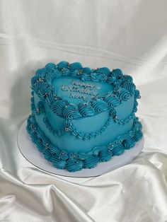 a blue heart shaped cake sitting on top of a white tablecloth covered table cloth