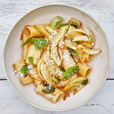 a white bowl filled with pasta covered in sauce and parmesan cheese sprinkled on top