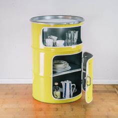 a blue metal container with plates and cups in it sitting on a wooden floor next to a white wall