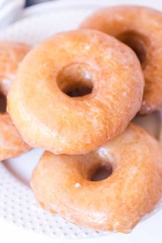 three glazed donuts on a white plate