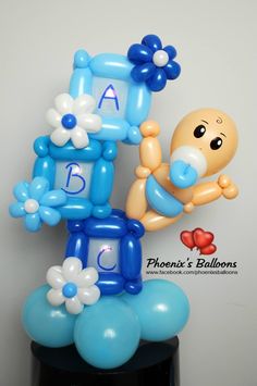 a blue and white balloon sculpture with a baby's first birthday decoration on top