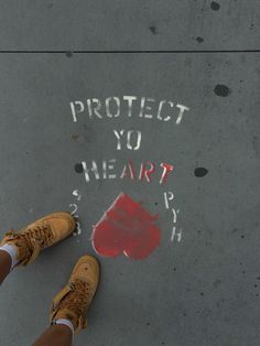 someone is standing on the sidewalk with their feet in front of them and writing that reads protect you heart