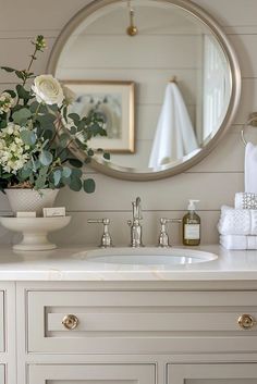 a bathroom sink with a mirror above it and flowers in a vase on the counter