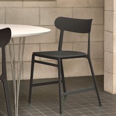 two chairs sitting next to each other in front of a white table and black chair