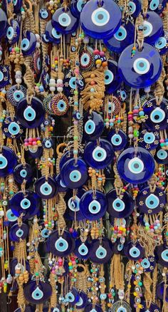 many blue plates and necklaces are hanging on the wall in front of each other