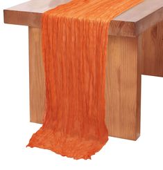 an orange table runner sitting on top of a wooden bench next to a piece of wood