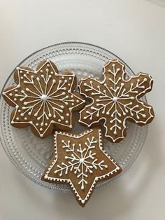 three decorated cookies sitting on top of a glass plate with snowflakes in the middle