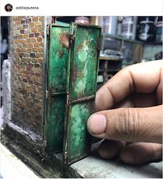 a hand is holding an old green door