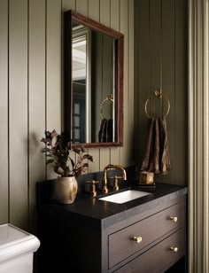 a bathroom with green walls and gold fixtures