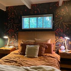 a large bed sitting under a window next to two nightstands with lamps on them